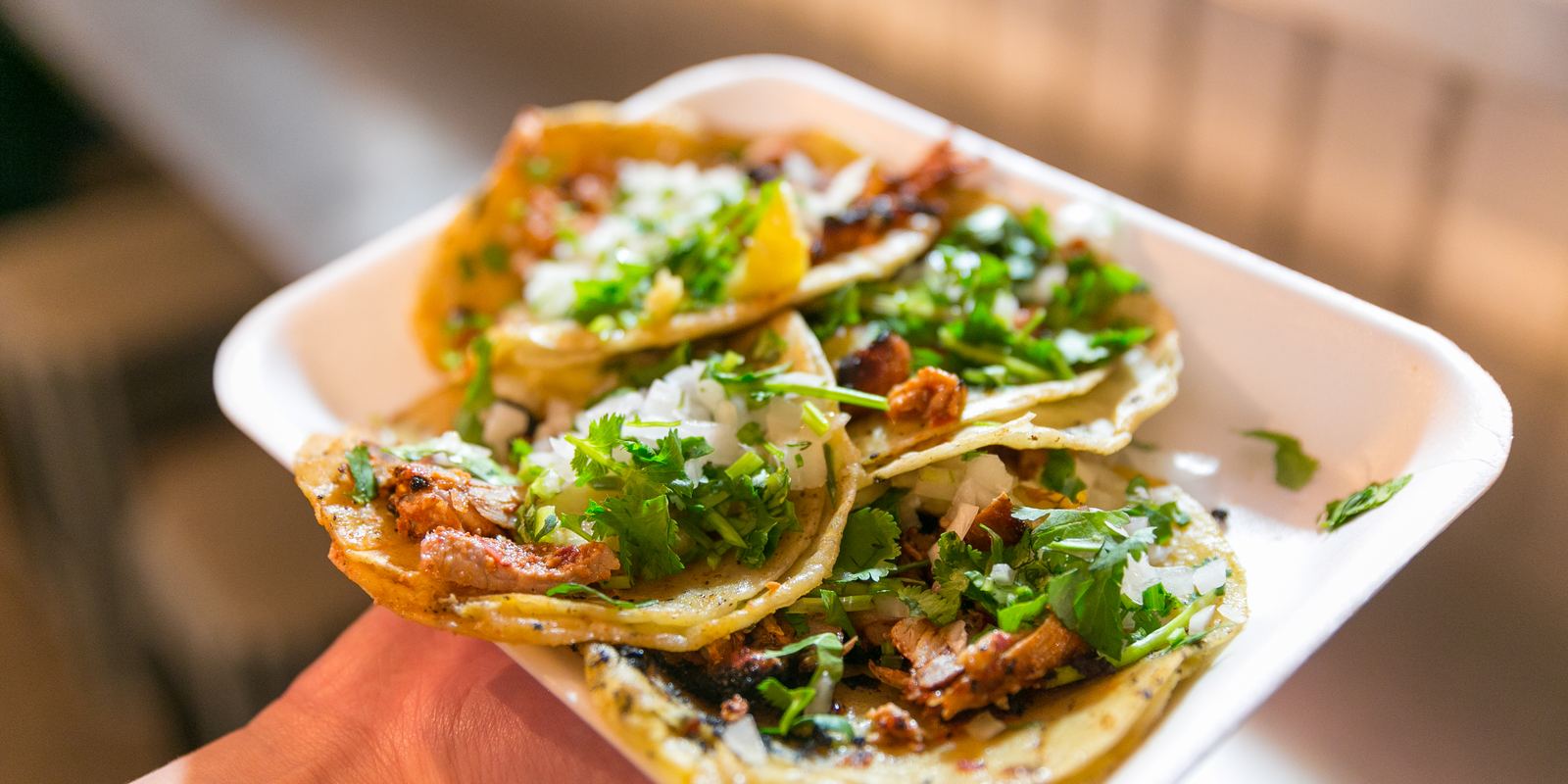 Three tacos al pastor topped with pineapple, onion and coriander